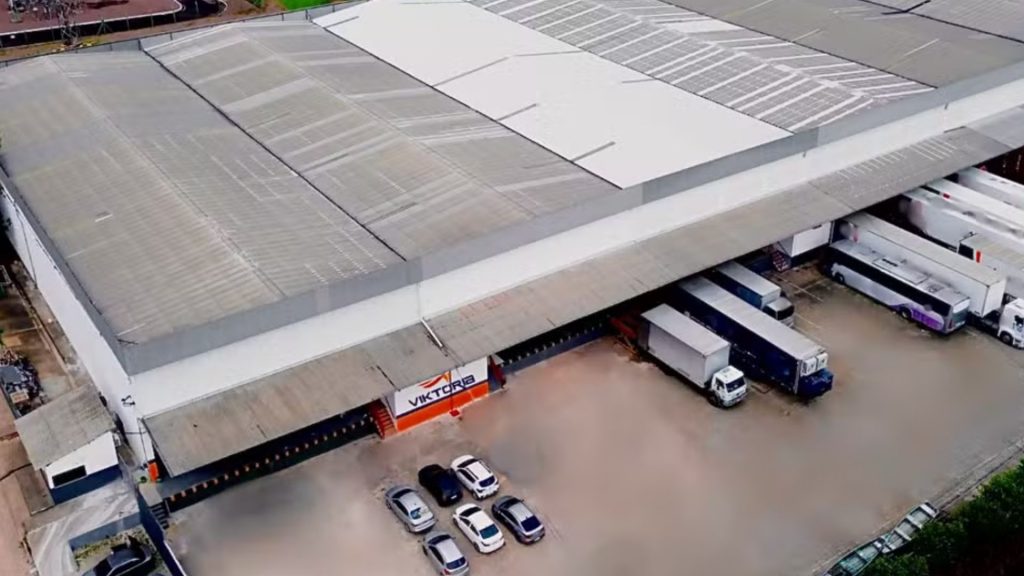 Vista aérea da sede da Viktória Cargas em Manaus, com caminhões e docas de carregamento em um grande armazém.